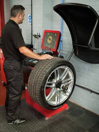 Technician balancing an alloy wheel and tyre on a computerised wheel balancer